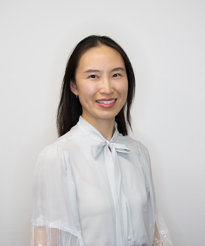 Echo Gu, smiling, in front of a white wall