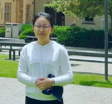 Shasha Zang, standing in the sunshine in the centre of the Parkville campus