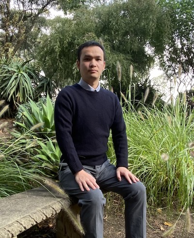 Lizhong Chen in the bush, surrounded by trees and long grasses