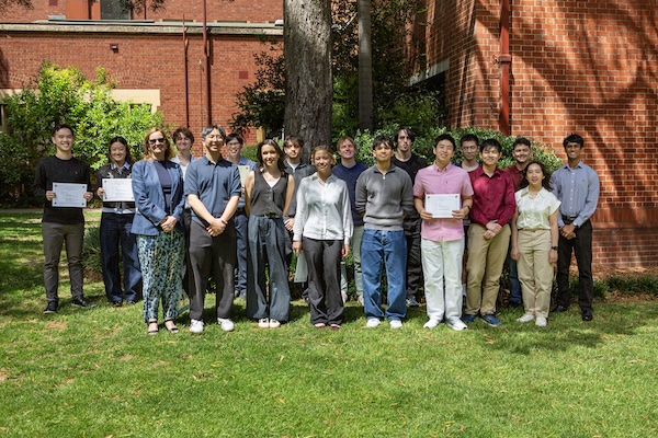 Students standing outside Peter Hall holding their certificates