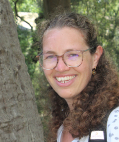 Portrait of smiling person with long curly hair and glasses